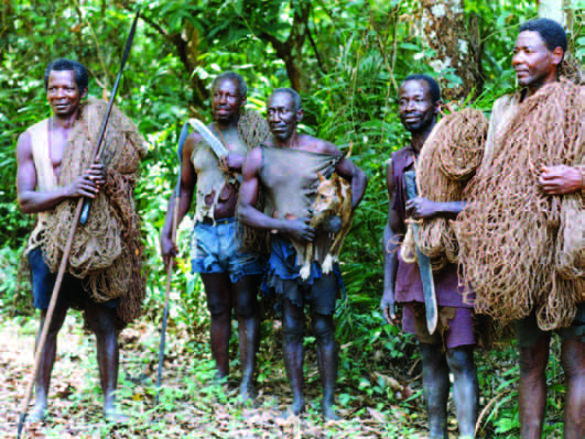 Hunters in central Africa with a basenji carried on a man's shoulder